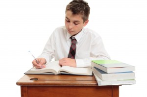 Un élève studieux sur son bureau en bois